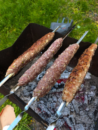 A grill with three skewers of meat on top of it.の写真素材