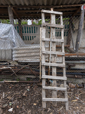 A wooden ladder leaning against a chain link fence.の写真素材