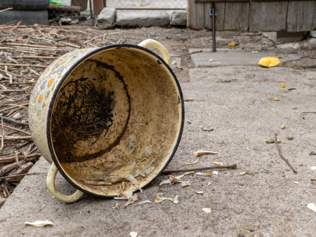 A dirty bucket sitting on the ground next to a fence.の写真素材