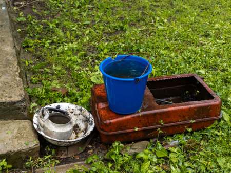 A blue bucket sitting on top of a metal box in the grass.の写真素材
