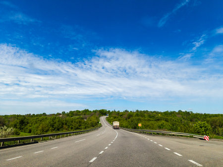 A truck driving down a highway with trees in the background.の写真素材