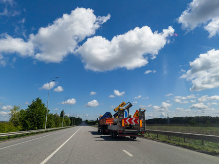 A truck driving down a highway under a blue sky with clouds.の写真素材