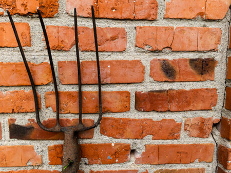 A pitchfork leaning against a brick wall.の写真素材