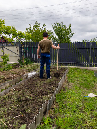 A man standing in a garden with a shovel in his hand.の写真素材