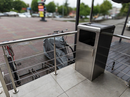A trash can sitting on the side of a street next to a bike rack.の写真素材