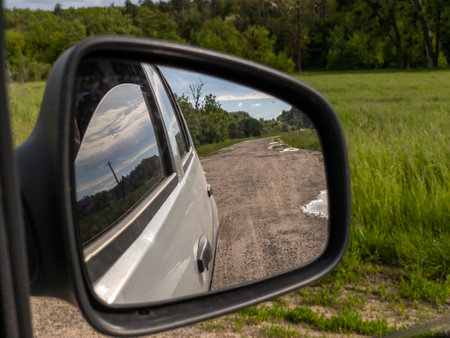 A side view mirror of a car on a dirt road.の写真素材