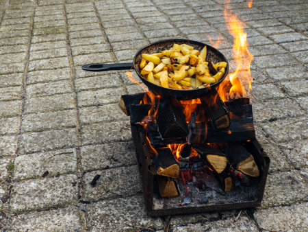 A pan of potatoes cooking over an open fire on a brick patio.の写真素材