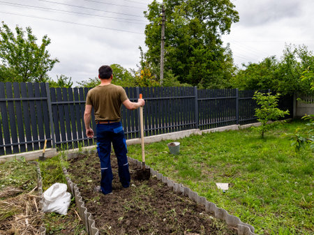 A man standing in a garden with a shovel in his hand.