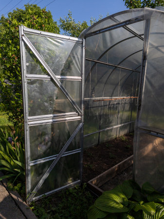 A greenhouse with a metal frame in the middle of a garden.の写真素材