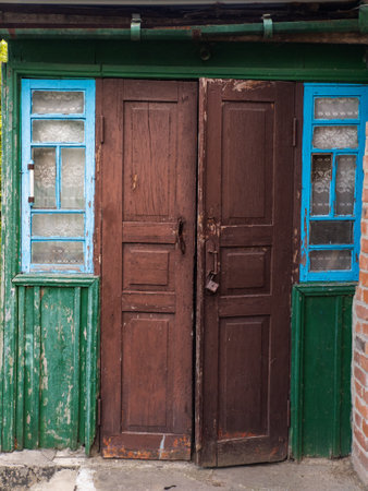 A pair of wooden doors with blue and green shutters on a brick building.の写真素材