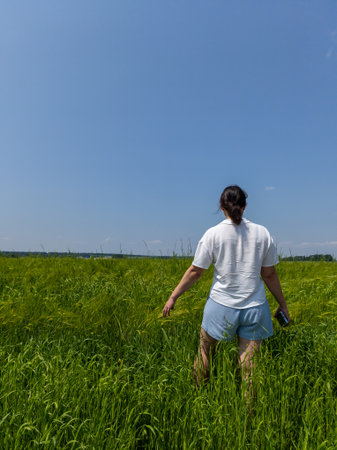 A woman walking through a field of tall grass.の写真素材