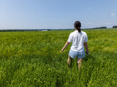 A woman walking through a field of tall green grass.の写真素材