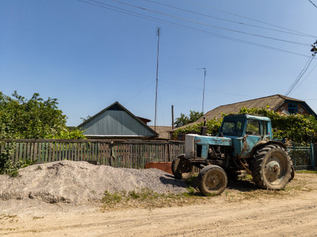 A blue tractor is parked on a dirt road.