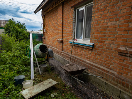 Construction work with concrete around a brick house, concrete mixer and wheelbarrow.の写真素材