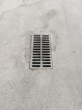 Metal sewage grate on the ground in the middle of the street.