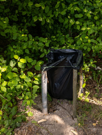 A black trash bag sitting on top of a wooden post in the woodsの写真素材