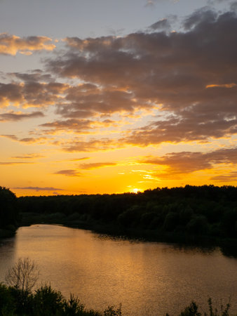 A sunset over a body of water with trees in the backgroundの写真素材