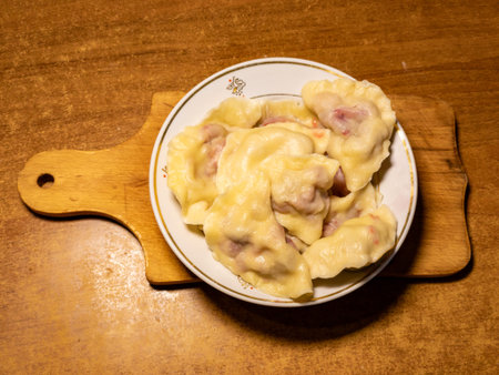 A plate of dumplings on a wooden cutting board on a table.の写真素材