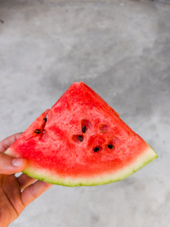 A person holding a slice of watermelon in their hand.の写真素材