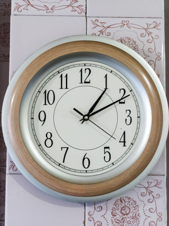 A white clock with black hands on a wall.