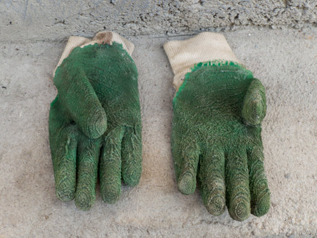 A pair of green gloves sitting on top of a cement floor.