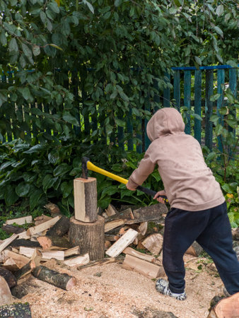 A young boy chopping wood with an ax in a garden.の写真素材