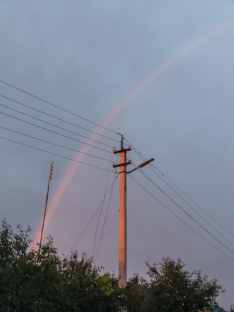 A double rainbow is seen in the sky over a telephone pole.の写真素材