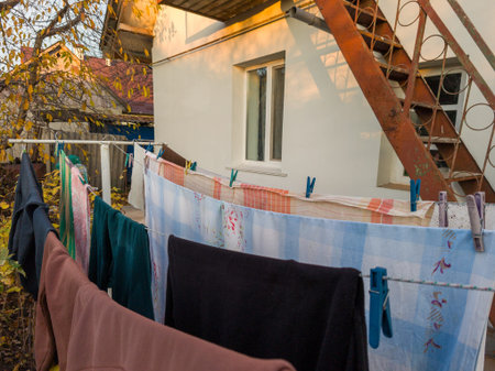 A line of clothes hanging out to dry on a clothes line outside of a house.
