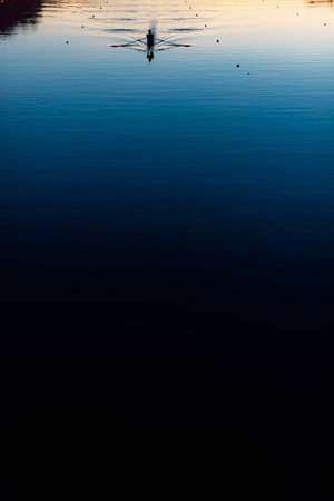 Lonely canoe kayak creating water ripples in calm sunset water canal sport rowing scenic sunset viewの写真素材