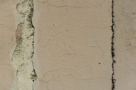 Grey texture of old broken asphalt road or wall big abrasions cracks on the surface pebbles cement