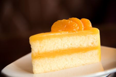 Orange cake on plate with blur brown backgroundの写真素材