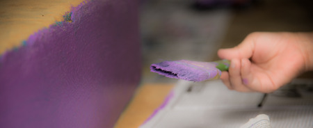 Blurred image of purple wall with paintbrush in handの写真素材