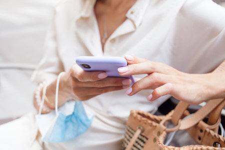 Close-up of woman hands using internet in her mobile phone outdoors, resting, after walking, taking...