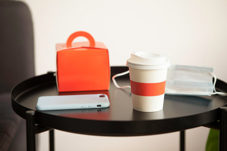Take away meal on the table in red design box and cup. Home delivery and stay home concept. Selective focus. Social distance during the pandemic and closed cafes and places of public catering.の写真素材