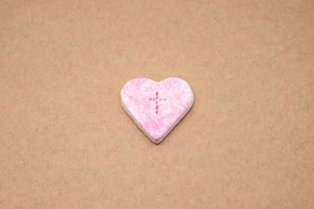 Crafted pink heart shape with cross symbol for religion and love backgroundの写真素材