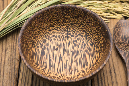 Empty wooden bowl with rice grains and leafsの写真素材
