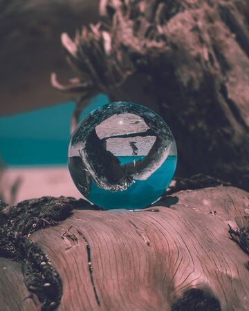 A lensball as the subject sitting on a driftwood at the beach. Shot at Elafonisos, Greece.の写真素材