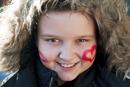 Painted happy child with heart and kiss on cheeksの写真素材