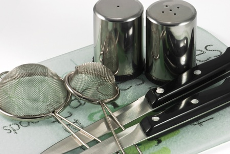 Kitchen utensils of stainless steel on ceramic plateの写真素材