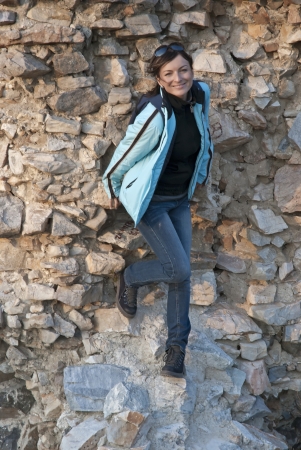 Beautiful woman standing by a stone wallの写真素材