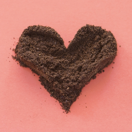 Ground coffee in the shape of heart on a red background.の写真素材
