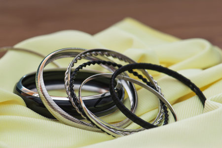 Metal bracelets on a yellow fabric.の写真素材