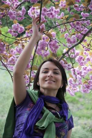 Beautiful woman under the blooming tree in spring. Sakura in arboretum.の写真素材