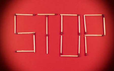 Word Stop made of matchsticks isolated on red background.の写真素材