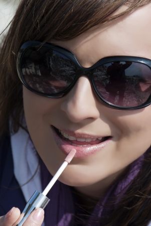 Beautiful woman applies lip gloss の写真素材