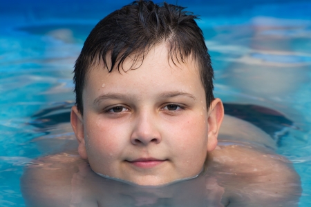 Young boy lying in swimming pool.の写真素材