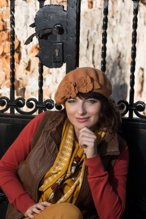 Happy beautiful brunette posing in front of a closed forged gate.の写真素材