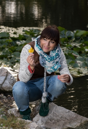 Beautiful woman holding yellow leaf in hand. Autumn theme.の写真素材