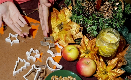 Woman cutting various gingerbread christmas cookies from the dough. Star in hand.の写真素材