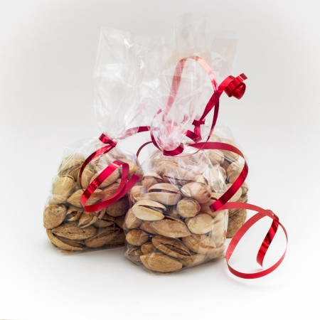 Pistachios in mini bags with red bows on a white background.の写真素材